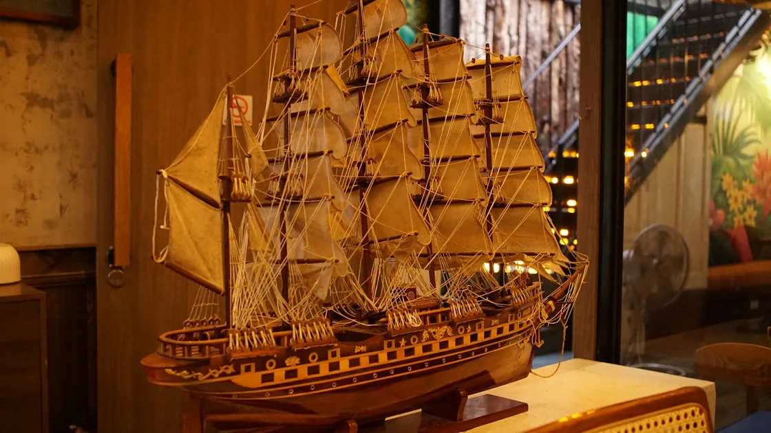 Modelo de velero de tres palos en madera, con velas y jarcia montadas, apoyado en su peana